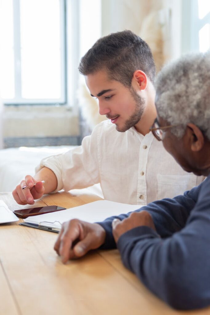 pexels-photo-7551629-7551629 Young man assisting senior adult with laptop at home for social needs.
